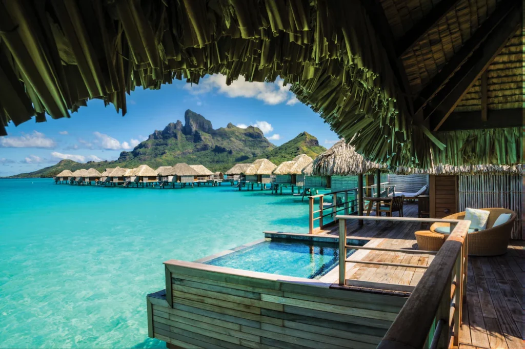 Luxurious overwater bungalow with glass floor panels and private deck overlooking the Bora Bora lagoon.