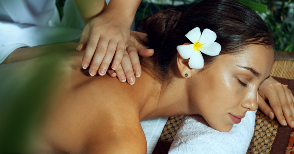 A woman enjoying a spa treatment with a flower in her hair.