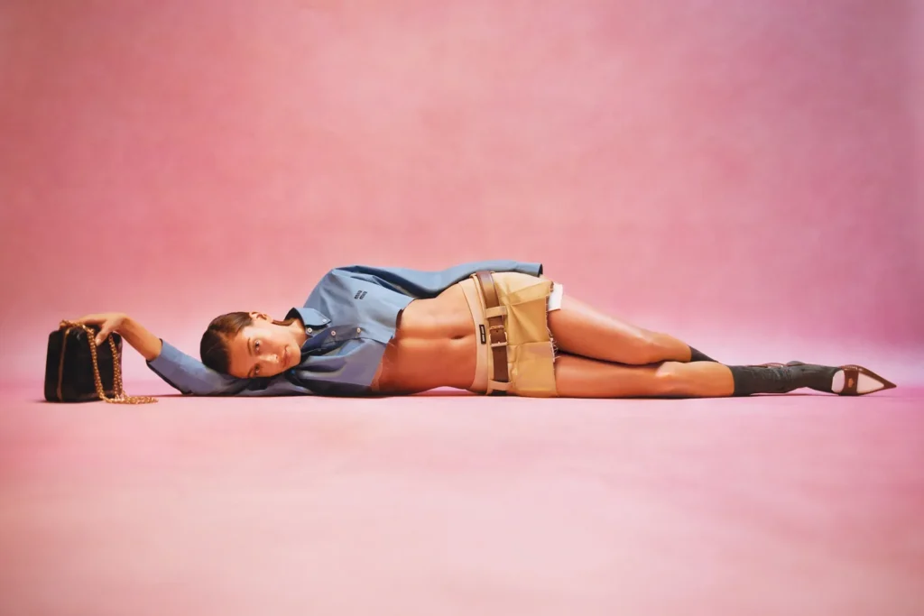 Gen Z Miu Miu fashion woman laying down with pink background