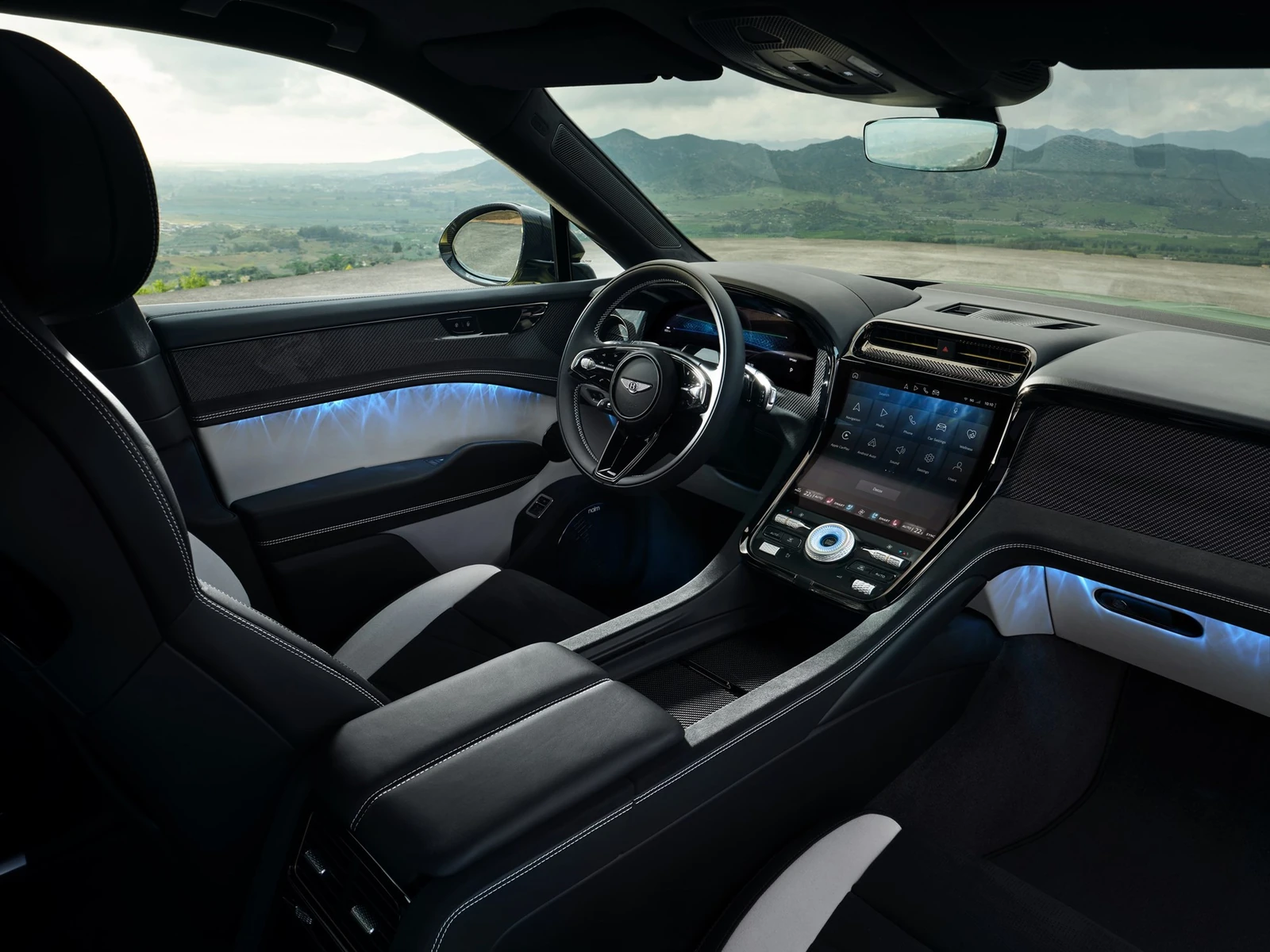 Bentley Torcal front cabin with curved central touchscreen, steering wheel, dark trim and illuminated door panels.