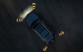 Blue Audi Q7 SUV seen from above on a dark surface with illuminated directional arrows around the vehicle.