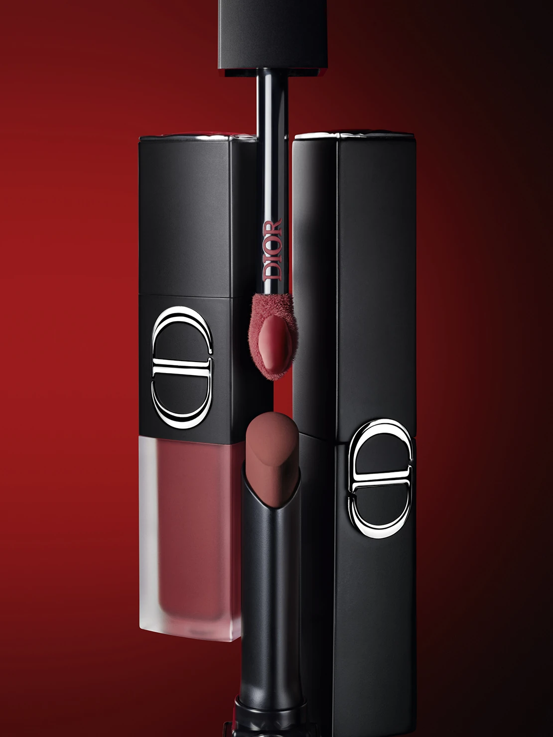 Rouge Dior On Stage lipstick and lip products in black Dior packaging against a deep red background.
