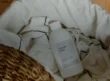 Unbranded laundry detergent bottle in a basket with white linens on a wooden floor.