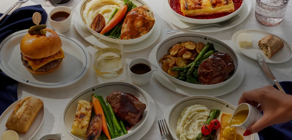 A selection of Delta One's newly announced main courses, including plated meals, bread, a burger and drinks.