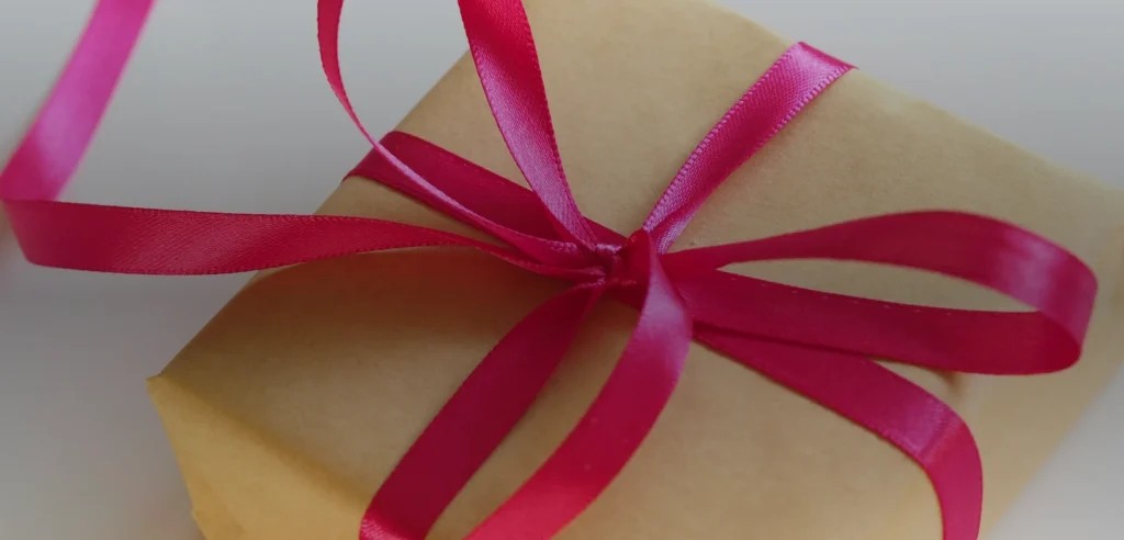 Ribbon-tied gift boxes arranged with evergreen sprigs on a tabletop.