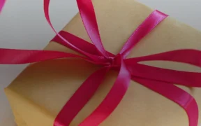 Ribbon-tied gift boxes arranged with evergreen sprigs on a tabletop.