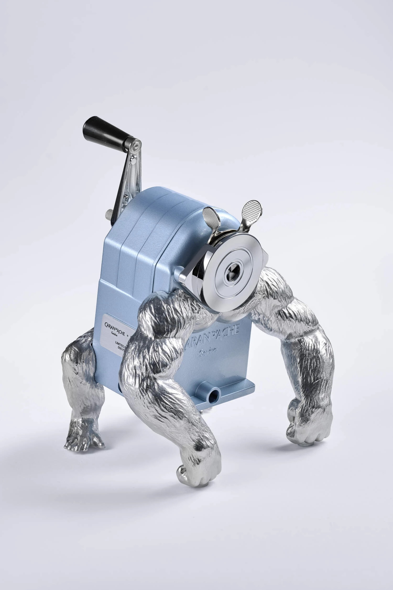 Caran d’Ache x MB&F GorillaSharpener in Alpine Frost blue, with a hand-crank sharpener body raised on silver gorilla-like limbs.